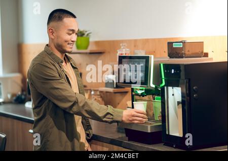 Büroangestellter, der ein koffeinhaltiges Getränk in der Unternehmensküche zubereitet Stockfoto