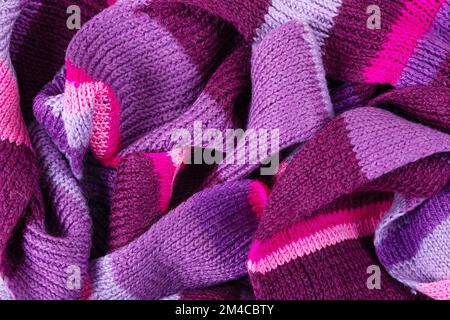 Gestrickter lilafarbener Hintergrund. Großer Strickstoff mit Muster. Wellenförmig faltet Material. Stockfoto