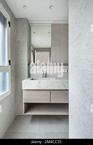 Toilette mit hellen Marmorfliesen, Schrank aus Marmor und niedrigen Holzschubladen Stockfoto