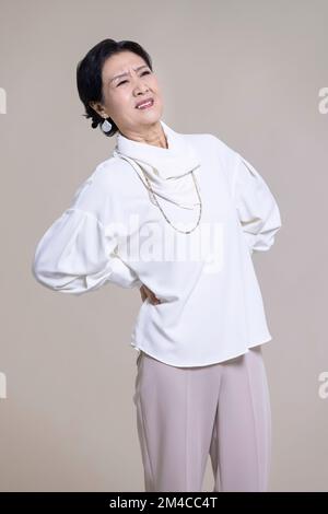 Ältere Chinesin mit Rückenschmerzen Stockfoto