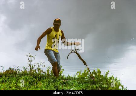 Reflexion im Wasser eines Mannes, der ein Seil am Ufer des Jaguaripe River in der Stadt Aratuipe, Bahia, zieht. Stockfoto