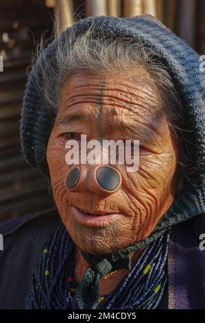 Ziro, Arunachal Pradesh, Indien - 02 19 2013 : Porträt der alten Apatani-Stammesfrau mit traditionellen Gesichtstätowierungen und Nasenstöpseln mit blauer Mütze Stockfoto