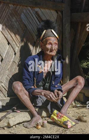 Mon, Nagaland, Indien - 11 25 2013 : Portrait des alten Naga Konyak-Stammesjäger-Kriegers mit traditionellem Gesichtstattoo, der einen Hut mit Eberstoßzähnen trägt Stockfoto