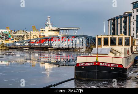 Hausboot, Iron Victoria Bridge und Offshore-Versorgungsschiff im Hafen von Leith im Winter mit gefrorenem Wasser des Leith River, Edinburgh, Schottland, Großbritannien Stockfoto