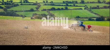 County Cork, Irland, 20. August 2022. Ein Traktor sät ein gepflügtes Feld in Irland. Landwirtschaftliche Arbeiten auf einem irischen Hof, Landschaftsbau, Traktor Stockfoto