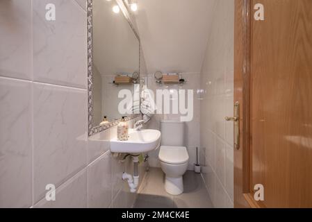 Kleine Toilette mit hängendem Porzellanwaschbecken ohne Schrank und Spiegel in der Wand Stockfoto