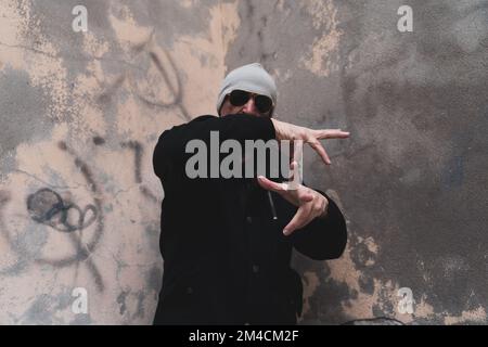 Reifer Rap-Sänger, der sich auf der Straße am Stadtrand einer Großstadt posiert Stockfoto