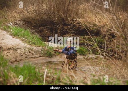 Junger Mann, der Angelrute im Bachwasser auswirft Stockfoto