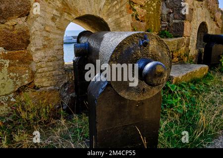 Unterwegs auf den Ertholmen-Inseln, historische Kanonen und Embrasuren an der befestigten Hafenmauer von Christiansö, Ertholmene, Dänemark. Stockfoto