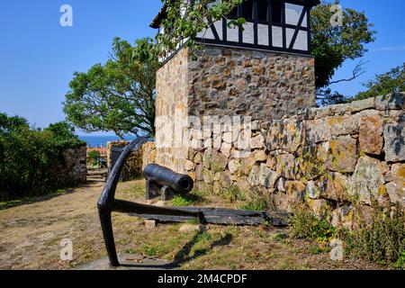 Unterwegs auf den Ertholmen-Inseln, alte Kanone und Schiffsanker vor dem abgetrennten Glockenturm der alten Kirche auf Christiansö, Ertholmene, Dänemark. Stockfoto