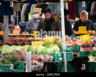 Gemüsehändler auf dem Walthamstow Market, London, Großbritannien, dem längsten Markt für Außenbereiche in Europa, mit Händlern und Händlern, die Käufer bedienen, mit Preisen in Pfund Sterling Stockfoto