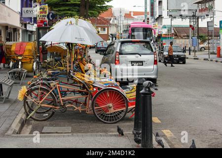 Georgetown, Penang, Malaysia - November 2012: Eine Reihe von bunt dekorierten Rikschas, die an der Straße in George Town, Penang, geparkt werden. Stockfoto