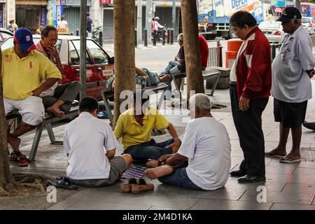 Georgetown, Penang, Malaysia - November 2012: Eine Gruppe alter Männer, die auf einem Straßenbelag in George Town, Penang, eine Runde Checkers spielen. Stockfoto