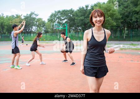 Fröhliche junge chinesische Freunde, die draußen Basketball spielen Stockfoto