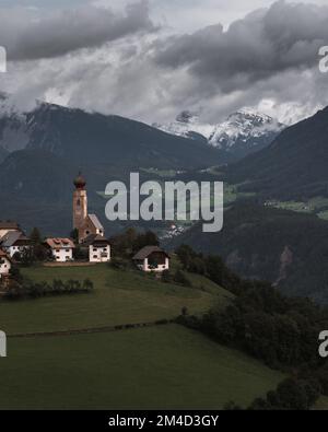 Ein vertikales Bild eines kleinen Dorfes in Mittelberg mit dem Kirchturm St. Nikolaus Stockfoto