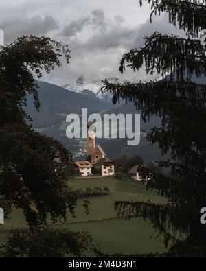 Ein vertikales Bild eines kleinen Dorfes in Mittelberg mit dem Kirchturm St. Nikolaus Stockfoto