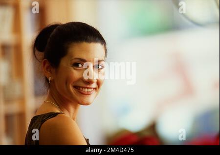 Eine jüngere Frau, die zurückblickt und in die Kamera lächelt Stockfoto