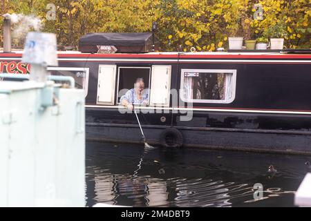 London, Vereinigtes Königreich - 17. Dezember 2022 strömt eine ältere Frau aus der Pfanne durch das Fenster des Bootes in den Kanal Stockfoto