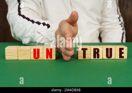 Geschäftskonzept. Ein Mann trennt die Würfel mit der Inschrift - UNWAHR oder WAHR Stockfoto