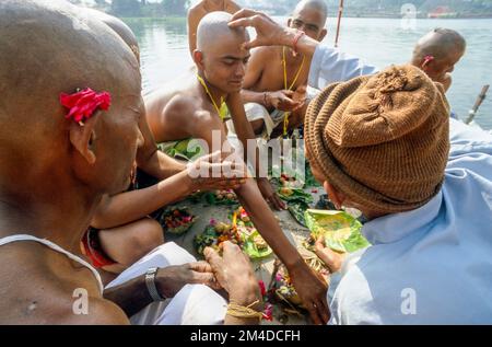 Ein Priester ist die Unterstützung von Beten Ritual für die gute Reinkarnation eines verstorbenen Person an Har-Ki-Pauri-Ghat in Haridwar Stockfoto