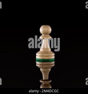 Weißer Schachbauer aus Holz, isoliert auf dunklem Hintergrund mit transparenter Reflexion auf dem Boden Stockfoto