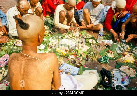 Ein Priester ist die Unterstützung von Beten Ritual für die gute Reinkarnation eines verstorbenen Person an Har-Ki-Pauri-Ghat in Haridwar Stockfoto