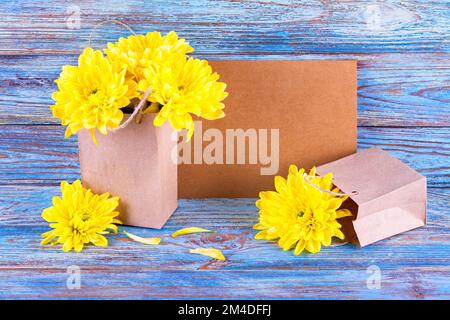 Gelbe Blüten einer Chrysantheme mit Geschenken und Platz für Grußtext, selektiver Fokus. Stillleben auf einem hölzernen Hintergrund Stockfoto