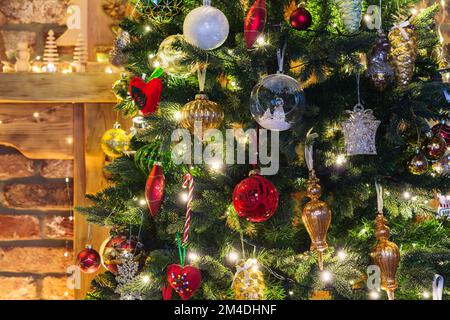 Nahaufnahme von geschmückten Weihnachtsbaum, der weihnachtsstern Blume, Christbaumkugeln, Lichterketten, selektive konzentrieren. Ziegelwand Hintergrund Stockfoto