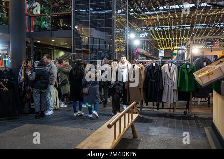 London, Großbritannien - 17. Dezember 2022 spazieren die Menschen am Abend im Licht der Girlanden durch den Spitalfields Designermarkt Stockfoto