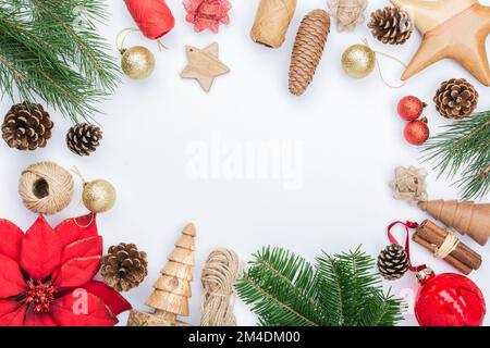 Weihnachtshintergrund, Kiefernzapfen, Holzornamente und -Dekorationen, Stoffblume, Zuckerstangen, Tannenbäume auf weißem Tisch Stockfoto