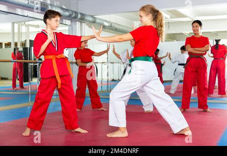 Gruppe von Kindern, die Karate-Kicks während des Karate-Kurses machen Stockfoto