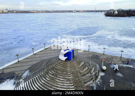 Großer Eisbär steht im Winter auf der Straße der Stadt, festliches Spielzeug. Die Leute gehen unter Weihnachtsdekorationen und Installationen. Dnipro, Ukraine 2022-01-02 Stockfoto