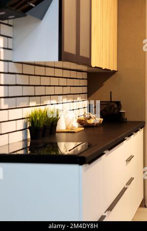 Modernes, stilvolles, kleines Küchenlayout. Küche mit schwarzer Arbeitsfläche und weißen Schränken. Selektiver Fokus. Stockfoto
