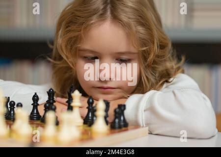 Junge und Schach, Nahaufnahme, Porträt, frühe Entwicklung. Das Kind denkt an Schach. Kinder Frühentwicklung. Ein Junge, der zu Hause Schach spielt. Hochformat geschlossen Stockfoto