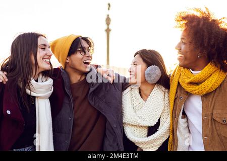 Multirassische Touristenfreunde in Winterkleidung, die ihren Urlaub in Barcelona genießen Stockfoto