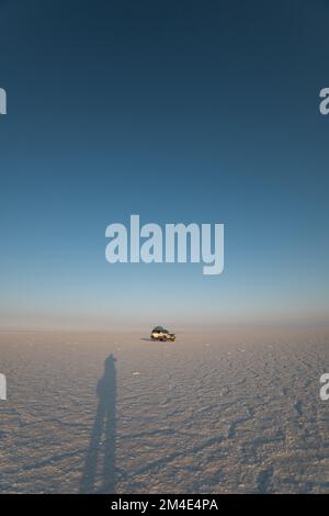 Ein Auto, das in einer Wüste mit klarem, sonnigen Himmel, Horizont von Sand und Himmel, Lebensstil und Transportmittel zu Land, Reisen fährt Stockfoto