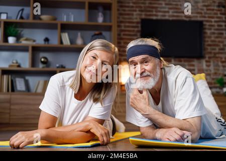Grauhaarige glücklich reifen älteren Paar macht Gymnastik zusammen zu Hause. Aktiver und gesunder Lebensstil für Rentner. Fitness, Erholung, gut Stockfoto