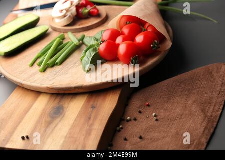 Holzbrett und frisches Gemüse auf grauem Hintergrund Stockfoto