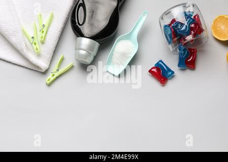 Waschmittel, Schaufel und Wäscheklammern auf grauem Hintergrund Stockfoto