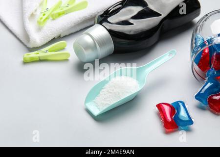 Waschmittel, Schaufel und Wäscheklammern auf grauem Hintergrund Stockfoto