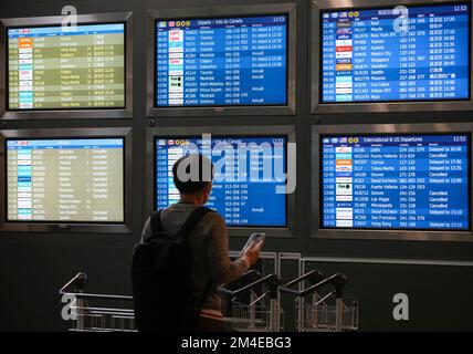 Richmond, Kanada. 20.. Dezember 2022. Ein Passagier liest am Vancouver International Airport in Richmond, British Columbia, Kanada, am 20. Dezember 2022 die Fluginformationen. Tausende von Reisenden saßen am Dienstag am Vancouver International Airport fest, da viele Flüge aufgrund des Schneesturms gestrichen oder verspätet wurden. Kredit: Liang Sen/Xinhua/Alamy Live News Stockfoto