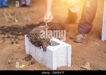 Die Hand eines Hispanos, der den ersten Block eines Werkes auf einem leeren Grundstück platziert Stockfoto