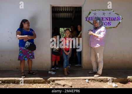 La Labor, La Libertad, Salvador - 27. Oktober 2022 - salvadorianische Frauen und Kinder an einem Eingang mit einem Schild mit der Aufschrift „Welcome“ Stockfoto