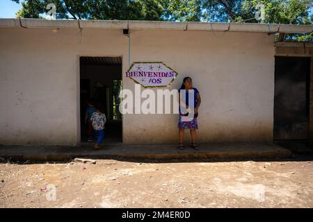 La Labor, La Libertad, Salvador - 27. Oktober 2022 - salvadorianische Frau wartet an einem Eingang mit einem Schild mit der Aufschrift „Welcome“ Stockfoto