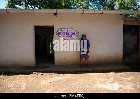 La Labor, La Libertad, Salvador - 27. Oktober 2022 - salvadorianische Frau wartet an einem Eingang mit einem Schild mit der Aufschrift „Welcome“ Stockfoto