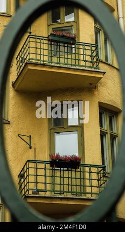 Ein vertikales Bild eines gelben Wohngebäudes mit rundem Objekt-Vordergrund Stockfoto