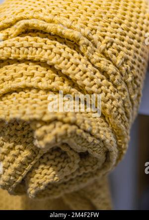 Beigefarbene, grob gestrickte Überdecke. Handgestrickte grobe Decke aus Merinowolle mit stilvoller und gemütlicher Innenausstattung. Wollgestrickstruktur Stockfoto