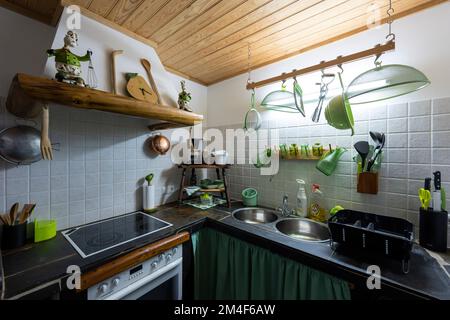 Die Retro-Küche des kleinen rustikalen Hauses mit weißen Fliesen und Holzdecke Stockfoto