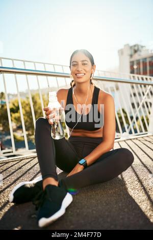 Ich halte nur kurz an, um zu tanken. Porträt einer sportlichen jungen Frau, die während des Trainings in der Stadt eine Pause macht. Stockfoto