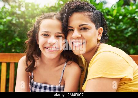 Sie ist mein Stolz und meine Freude. Verkürztes Porträt einer jungen Frau und ihres bezaubernden kleinen Mädchens, das auf einer Bank im Park sitzt. Stockfoto